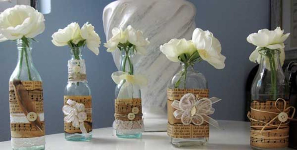 floreros con botellas de vidrio con papel y lazos